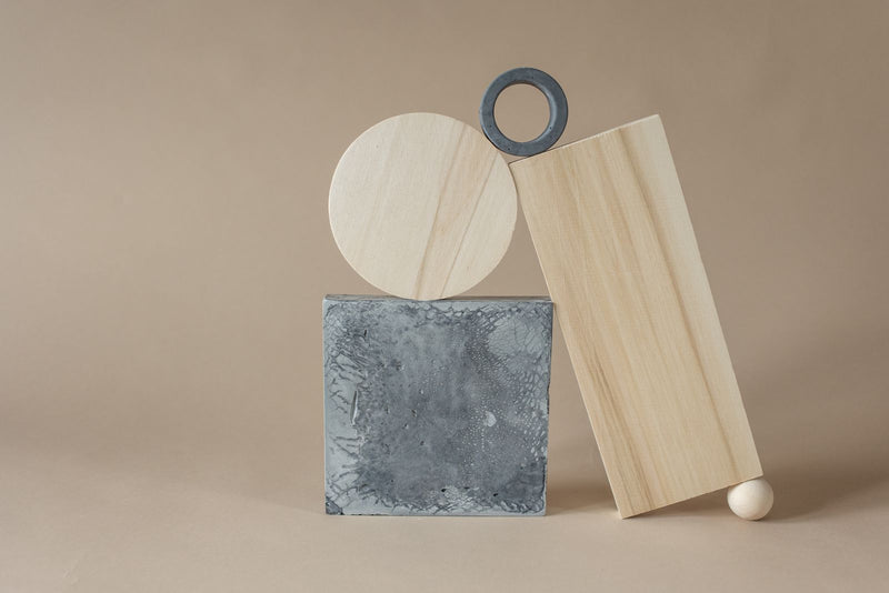 Disque de bois clair, dalle de béton et anneau de métal en équilibre, l'image d'un cadeau utile qui ne se jette pas