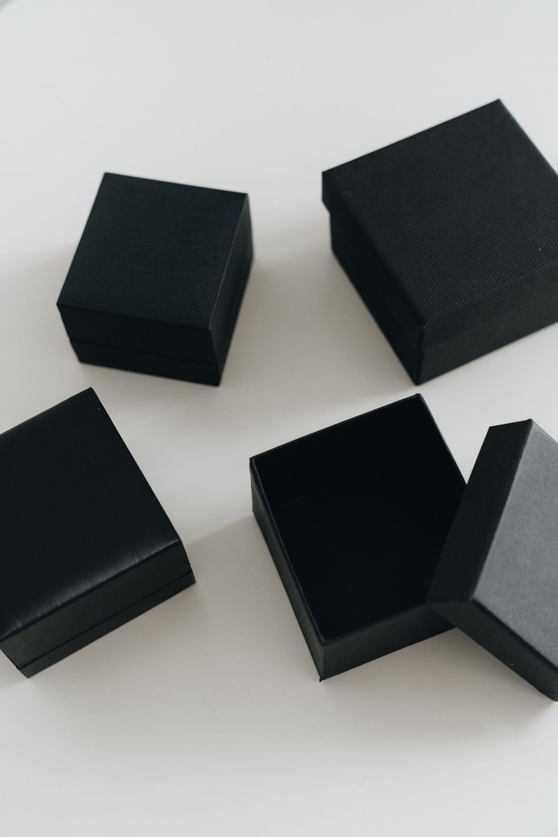 Coffret cadeau de parfum d'intérieur : écrins noirs minimalistes posés sur une table claire