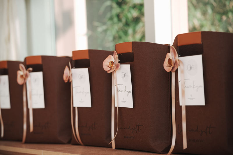 Sacs cadeaux élégants alignés sur une table claire, offrir un parfum d'intérieur sans se tromper