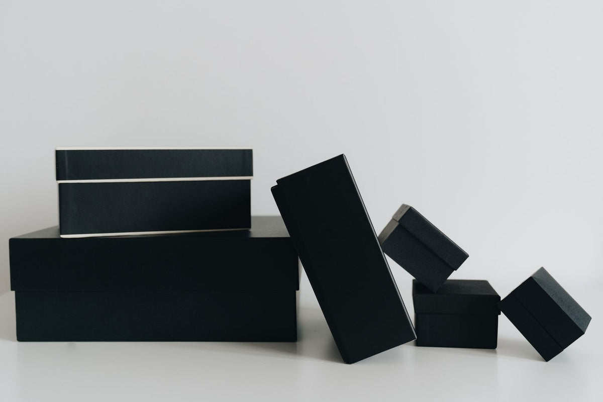 Coffrets cadeaux noirs et minimalistes posés sur une table : quel diffuseur de parfum offrir selon la personne