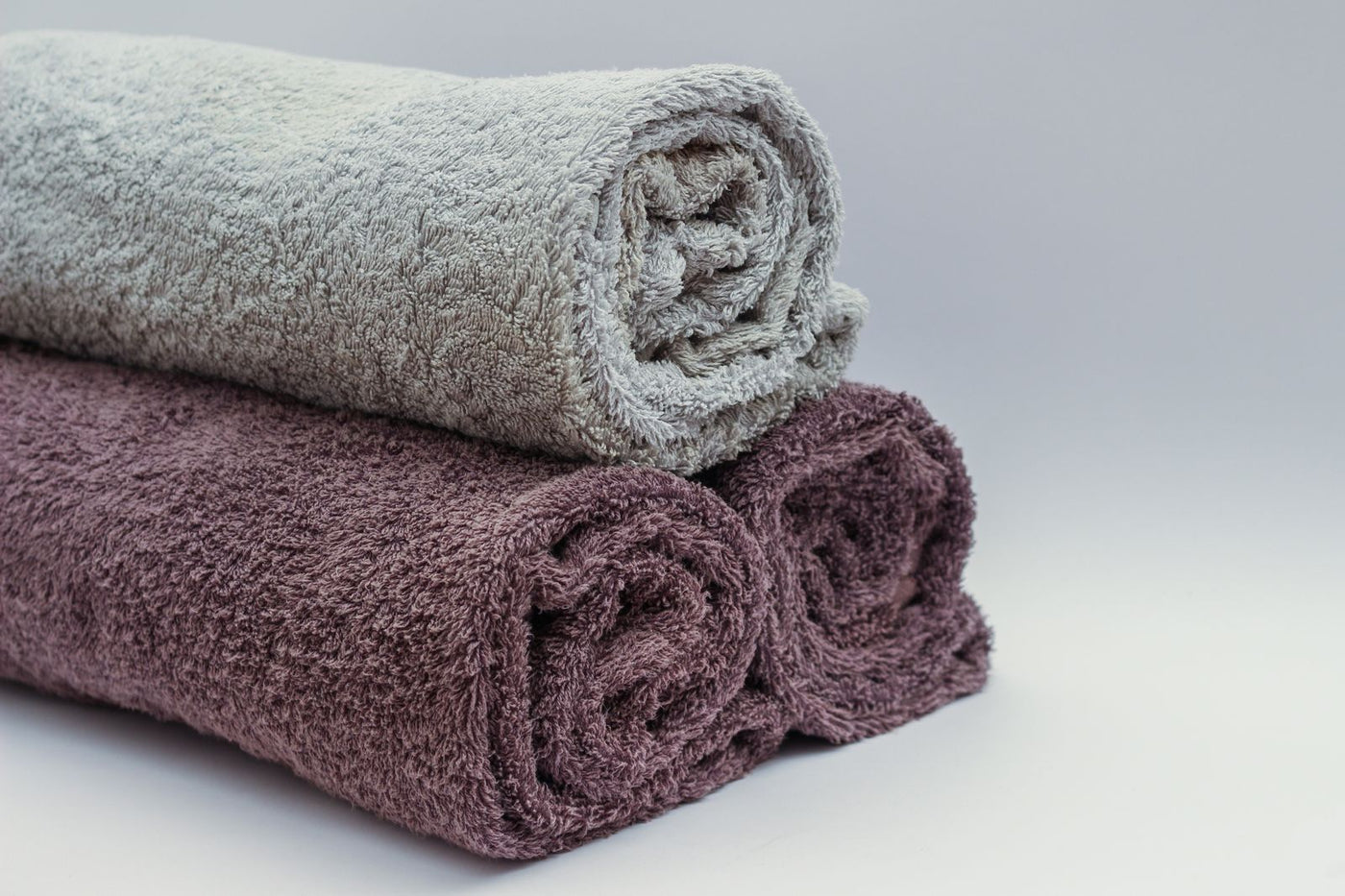 Textiles clairs roulés dans un intérieur épuré, ambiance entretenue par une recharge diffuseur PURRA